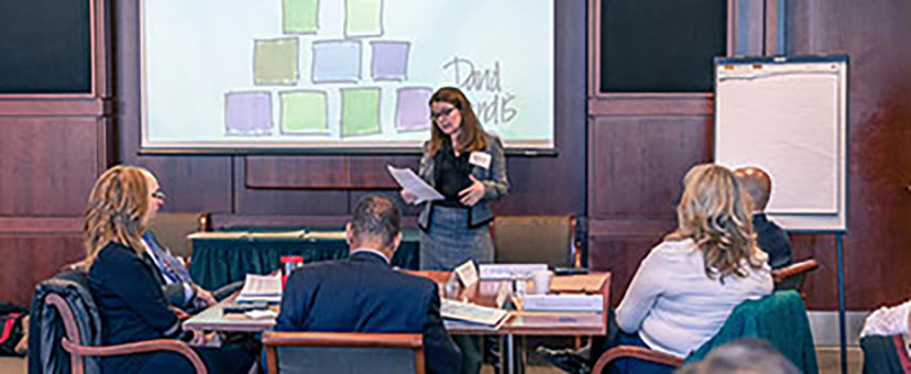 Speaker in front of a projection screen at an event with seated attendees