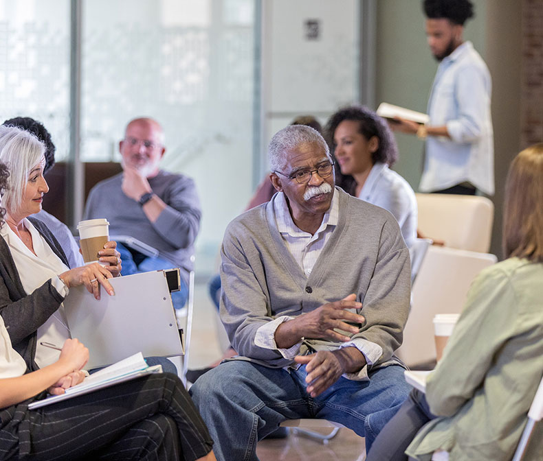 Group of people in conference with aa senior man speaking